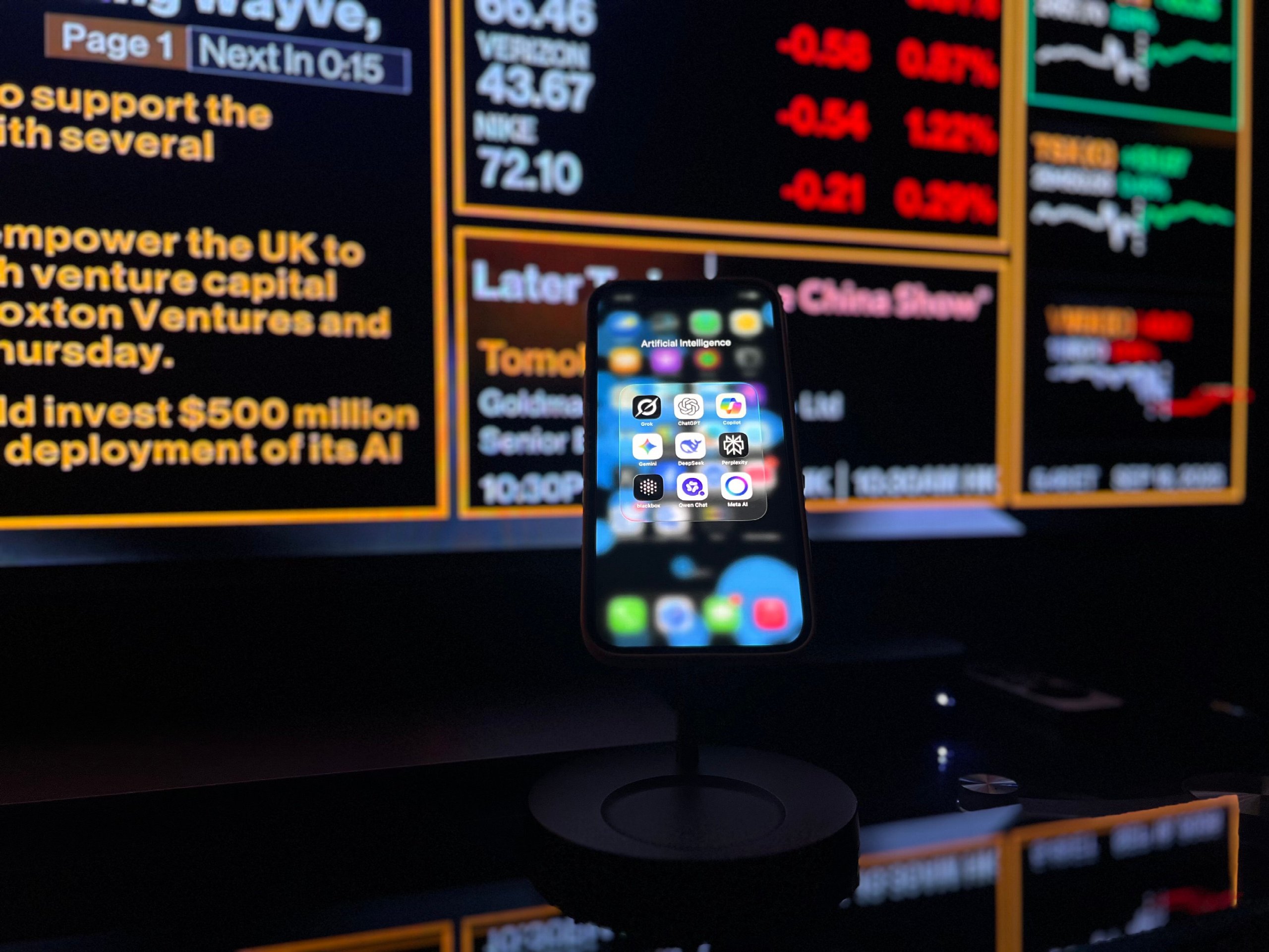Smartphone with AI apps in front of financial market data screens