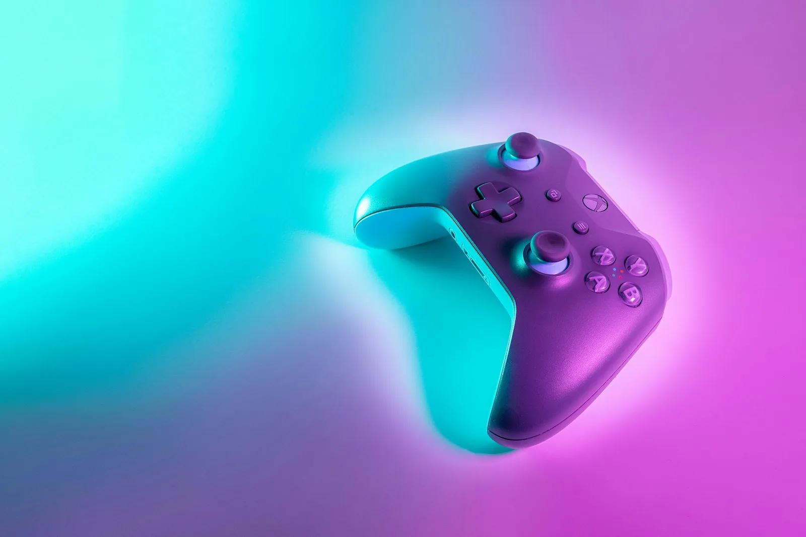 Wireless game controller lit by cyan and magenta neon light